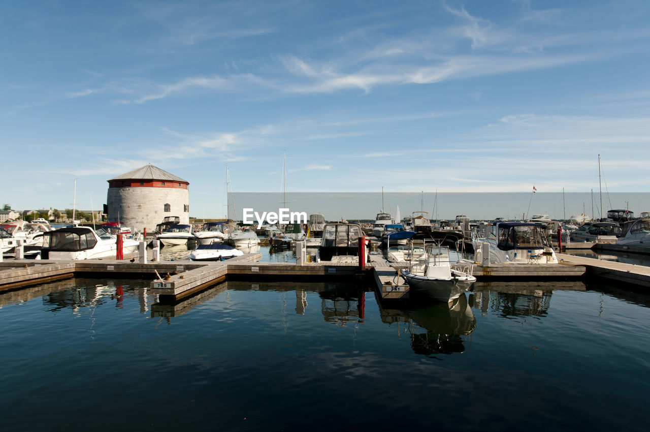 Boats moored at harbor against sky