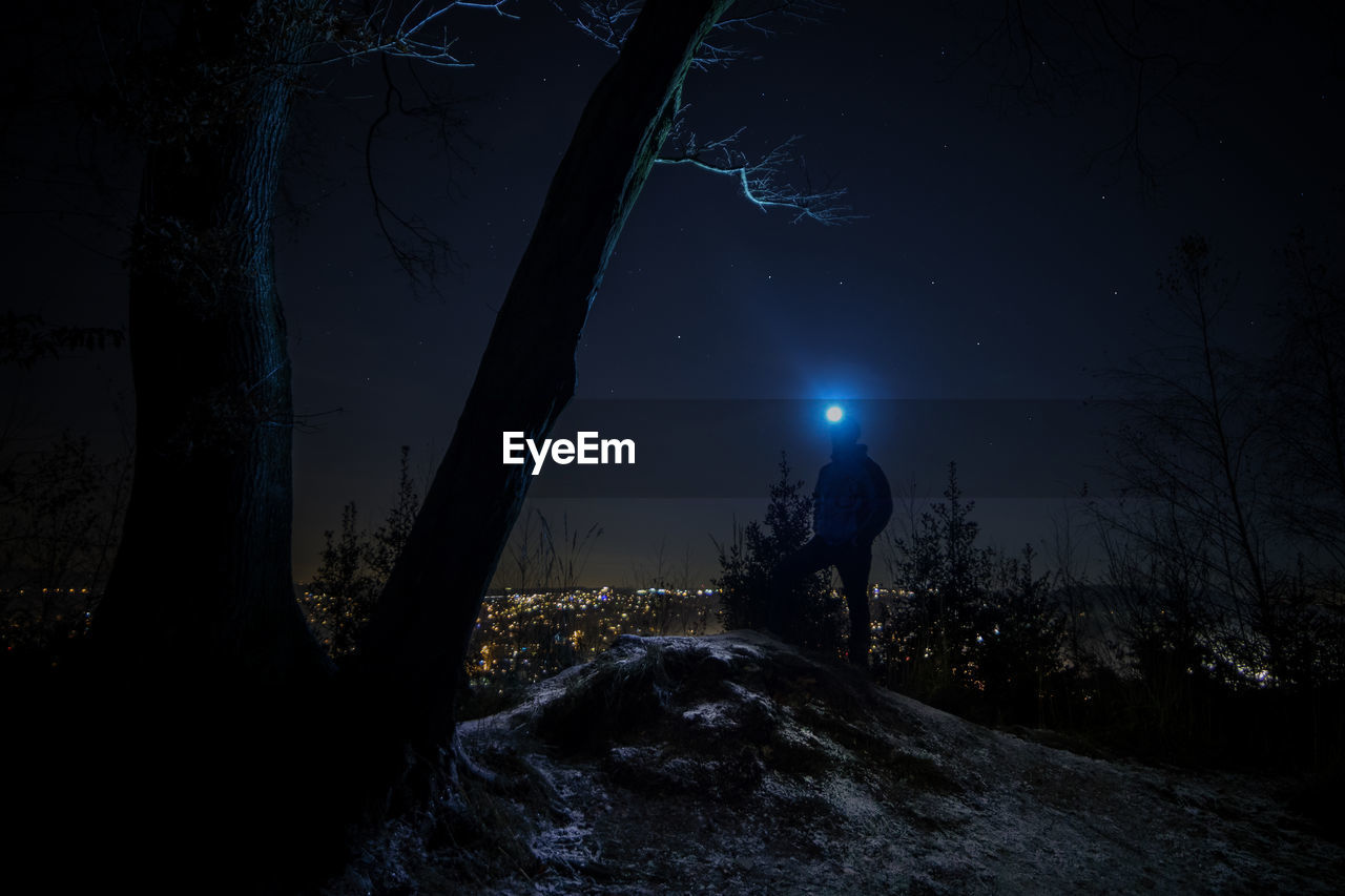 Full length of person in forest against sky at night during winter