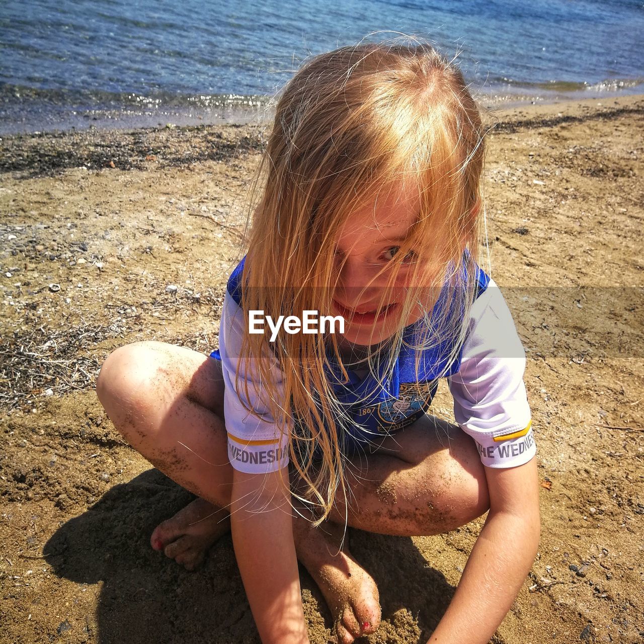 GIRL SITTING ON SHORE AT BEACH