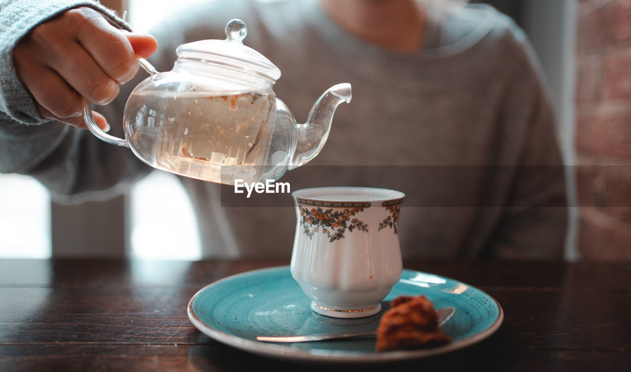 Midsection of woman holding coffee cup on table