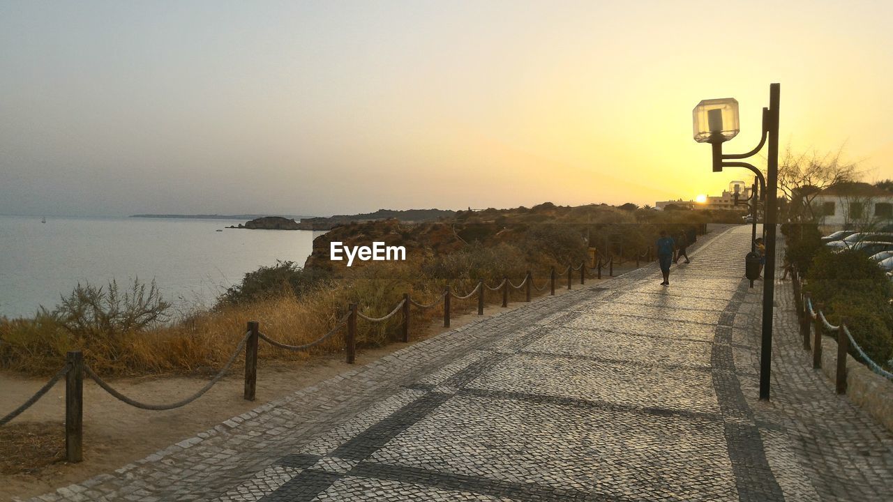 FOOTPATH BY STREET AGAINST CLEAR SKY DURING SUNSET