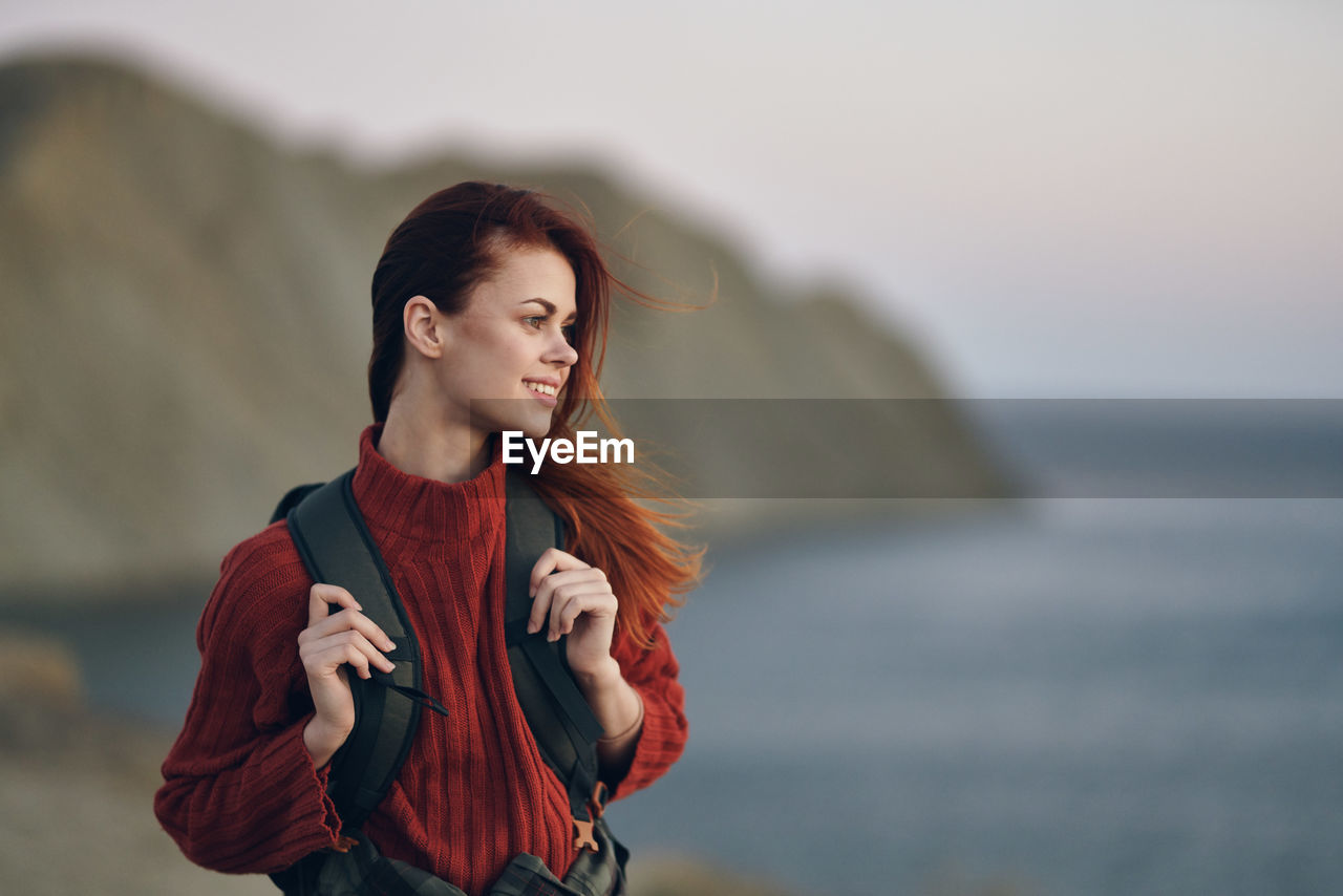 BEAUTIFUL YOUNG WOMAN LOOKING AWAY AT SEA