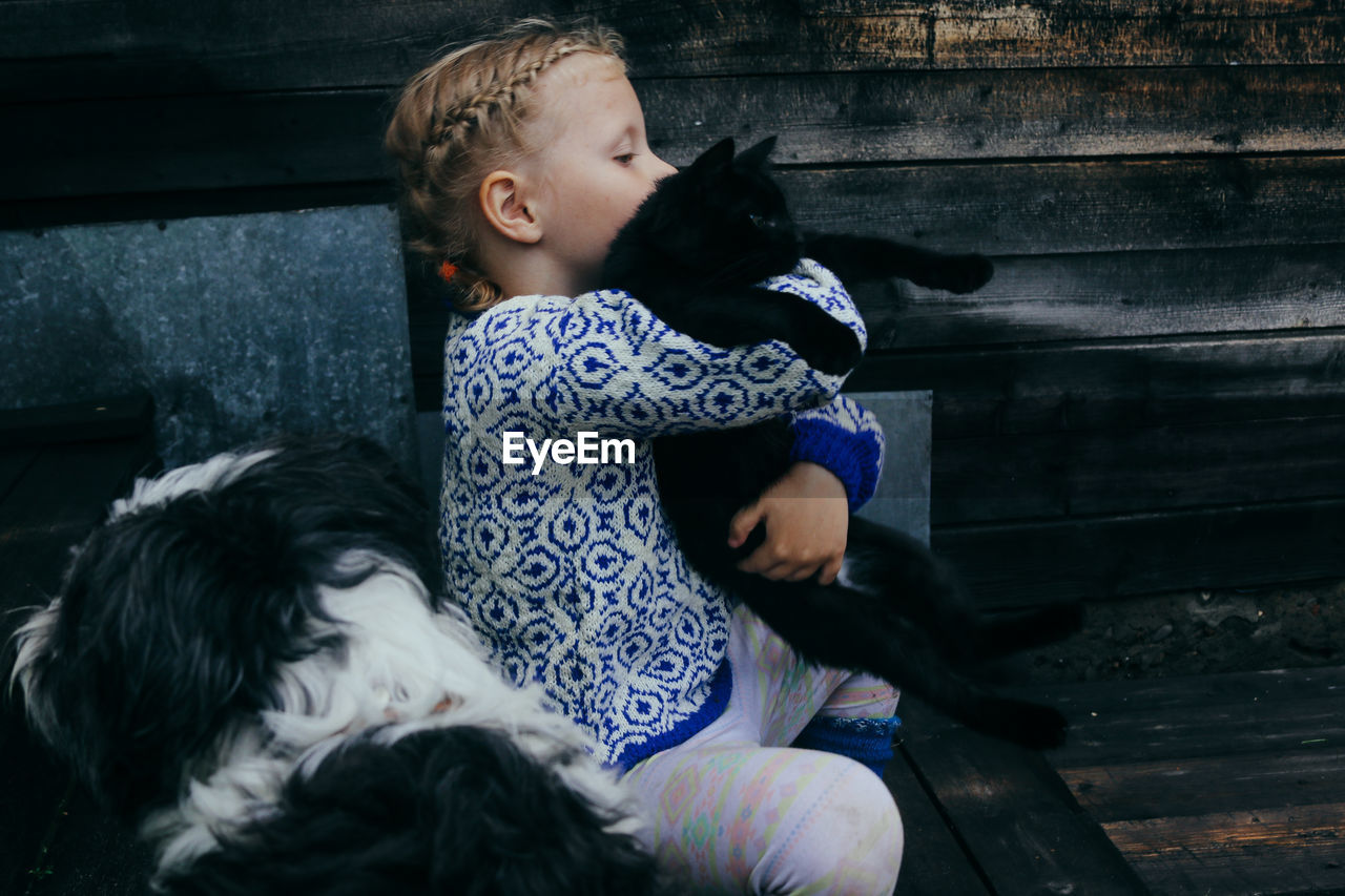 Girl in a knitted sweater and knitted socks sits on the porch with pets