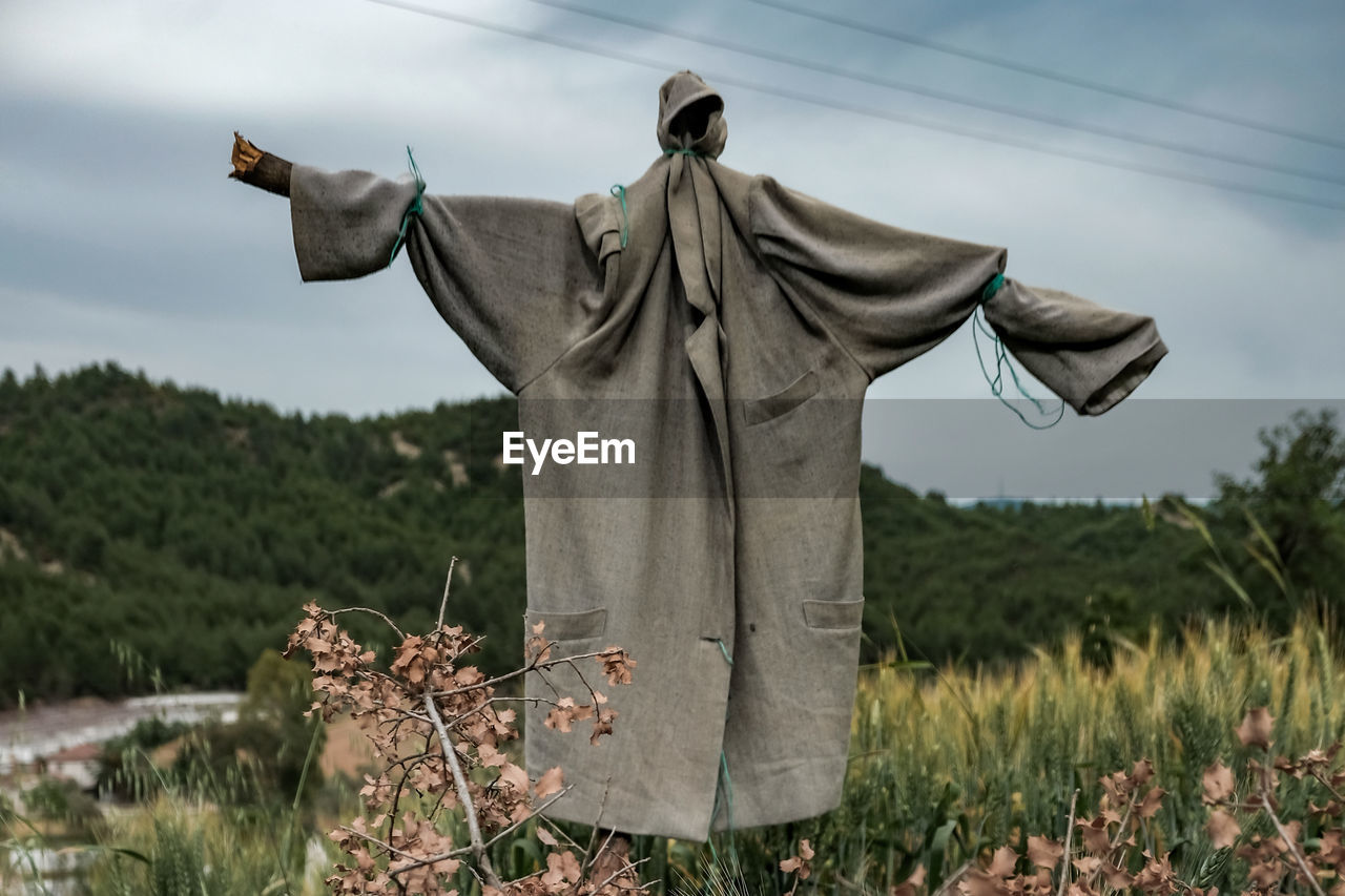 CLOTHES HANGING ON FIELD AGAINST SKY