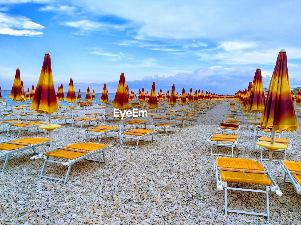 Panoramic view of empty chairs at beach against sky