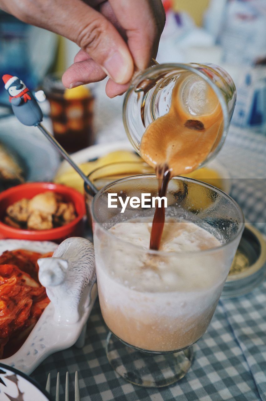 CROPPED IMAGE OF PERSON POURING DRINK IN GLASS