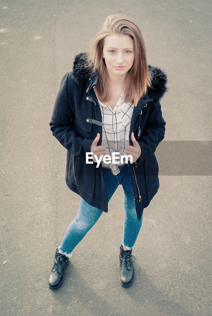 High angle portrait of young woman wearing warm clothing while standing on road