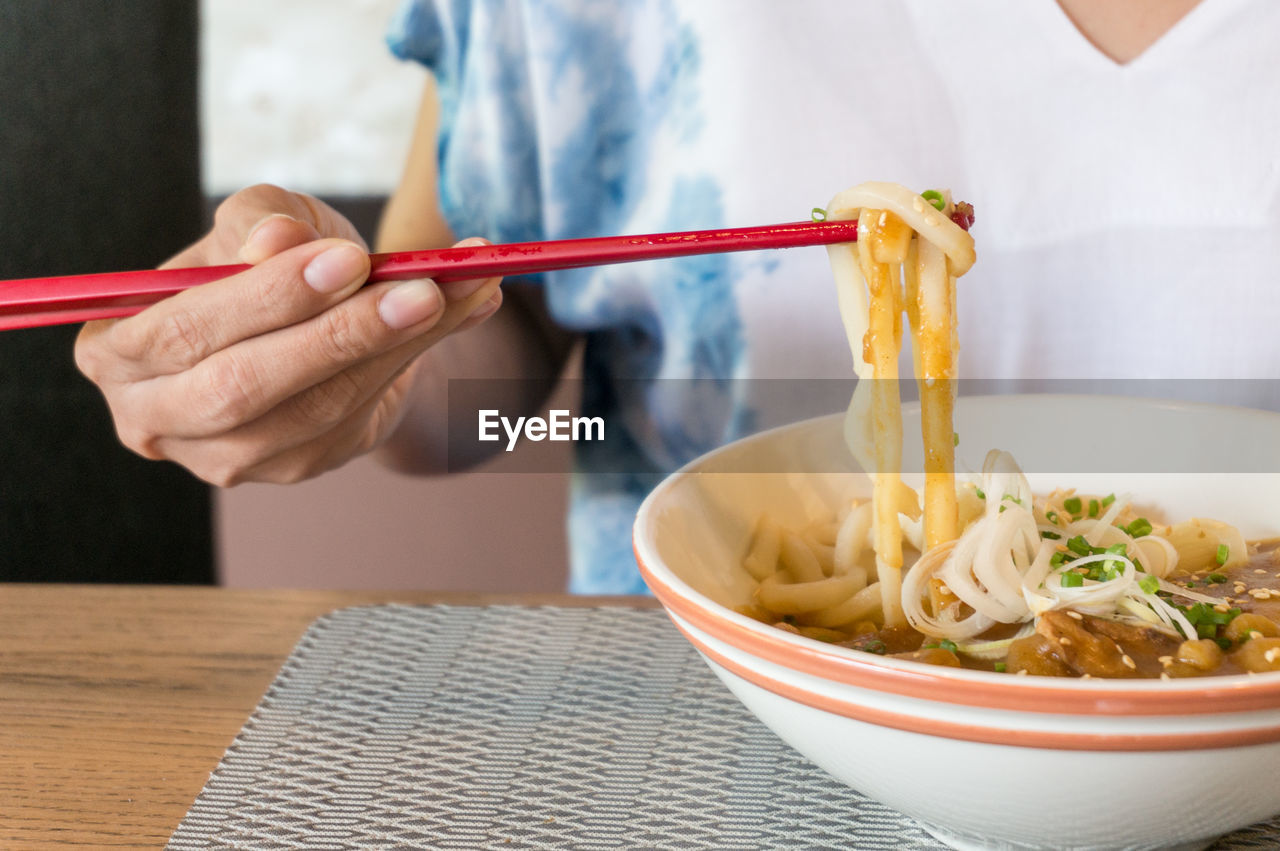 Midsection of woman having soup at table