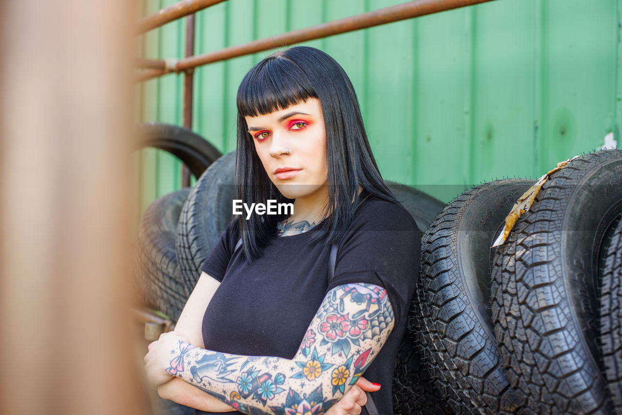 Portrait of young woman standing by wheels