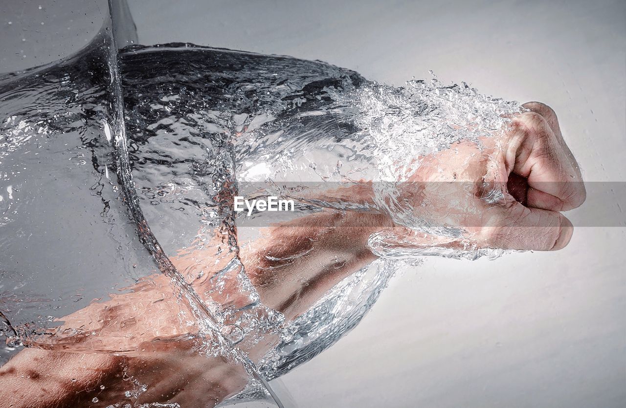 Digital composite image of man punching water against wall
