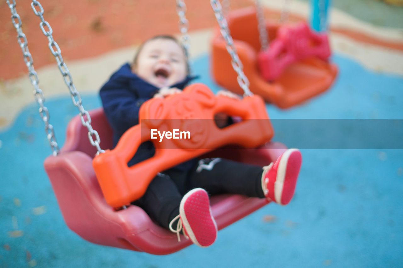 Baby boy sitting on swing at park