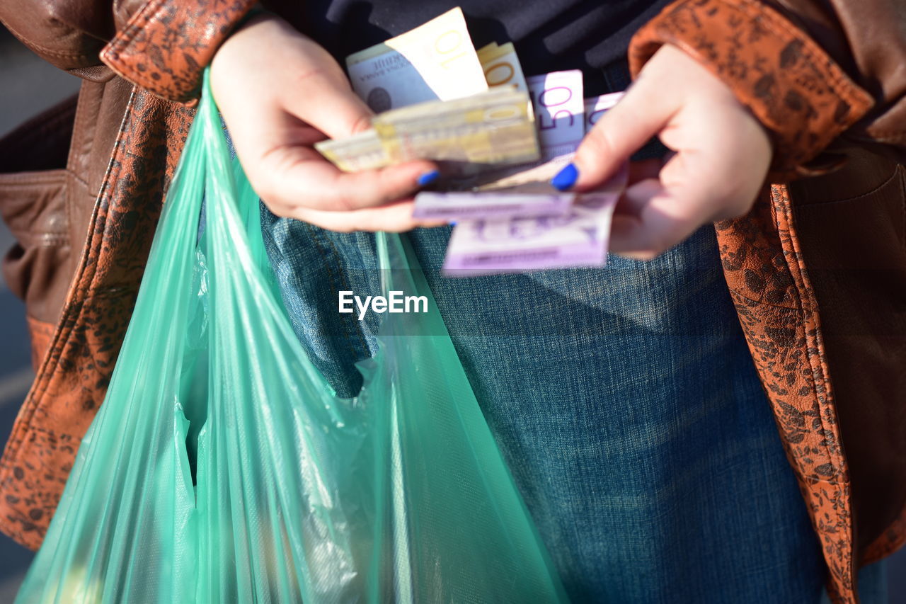 A woman counting serbian dinars with a plastic bag in her hands