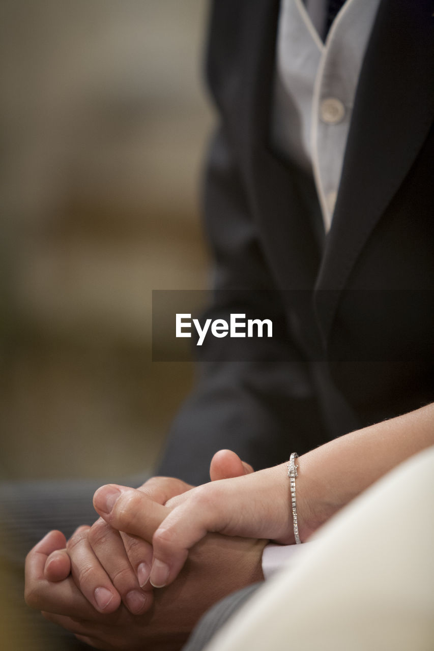 Midsection of couple holding hands during wedding ceremony