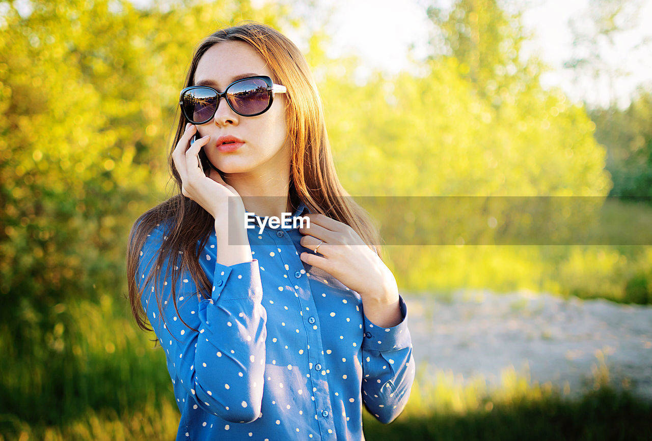 Beautiful young woman looking away while talking on phone outdoors