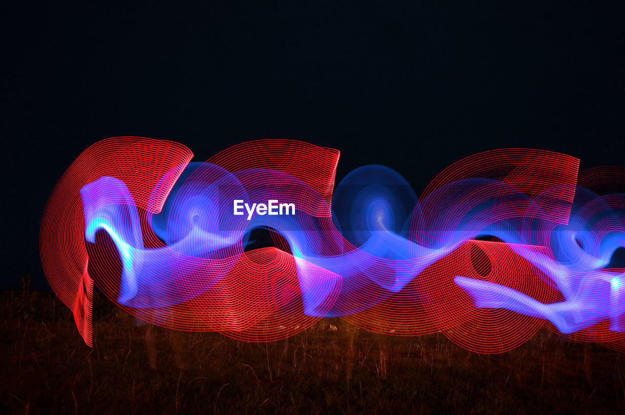 Illuminated light painting against sky at night