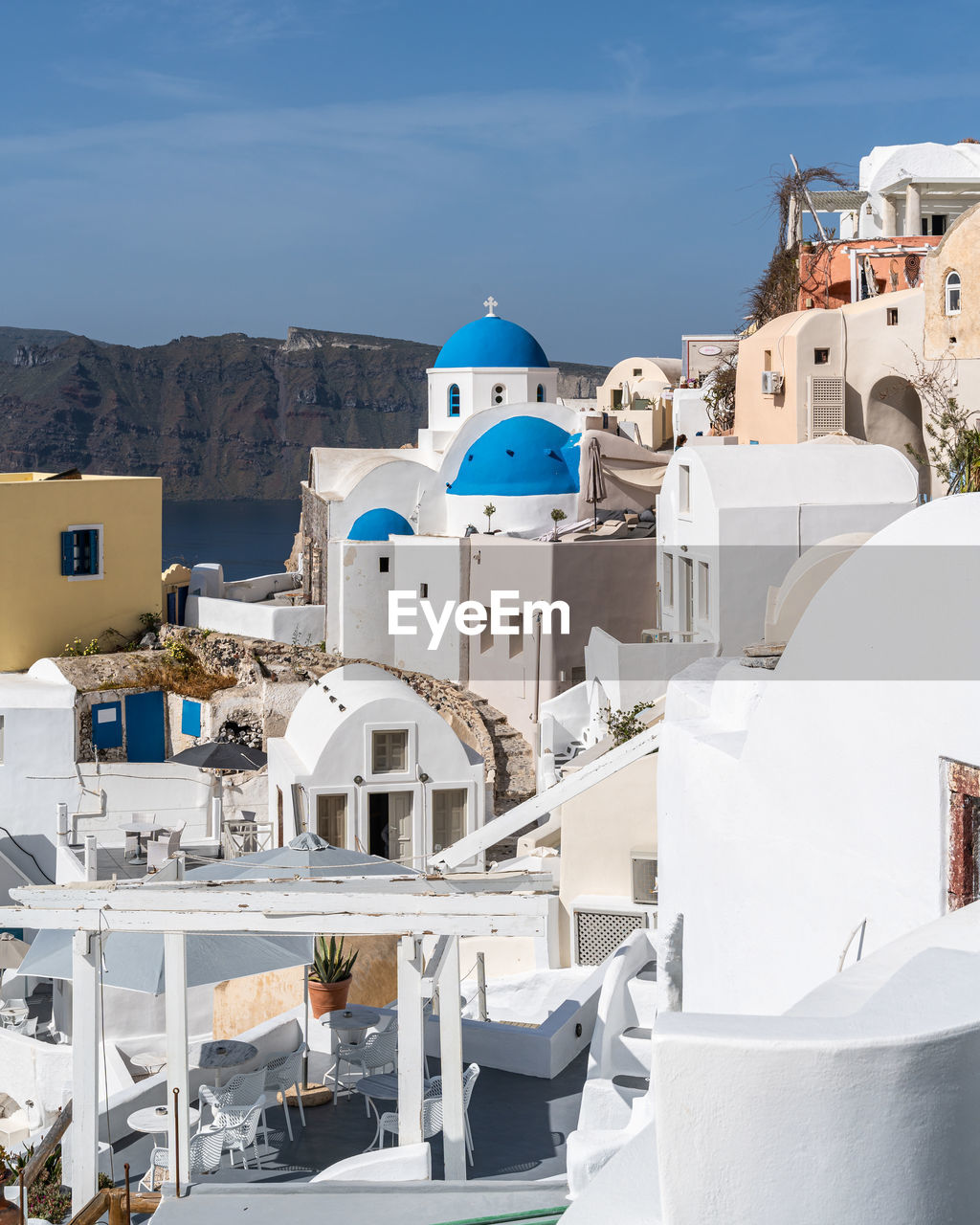 View of oia village in santorini with traditional white houses and blue domes churches, greece