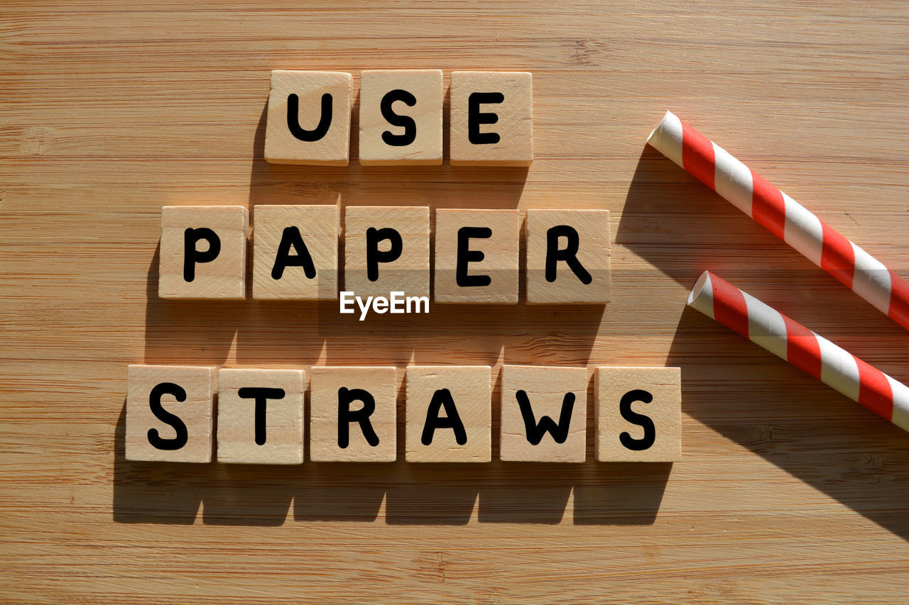 High angle view of information sign by straws on table