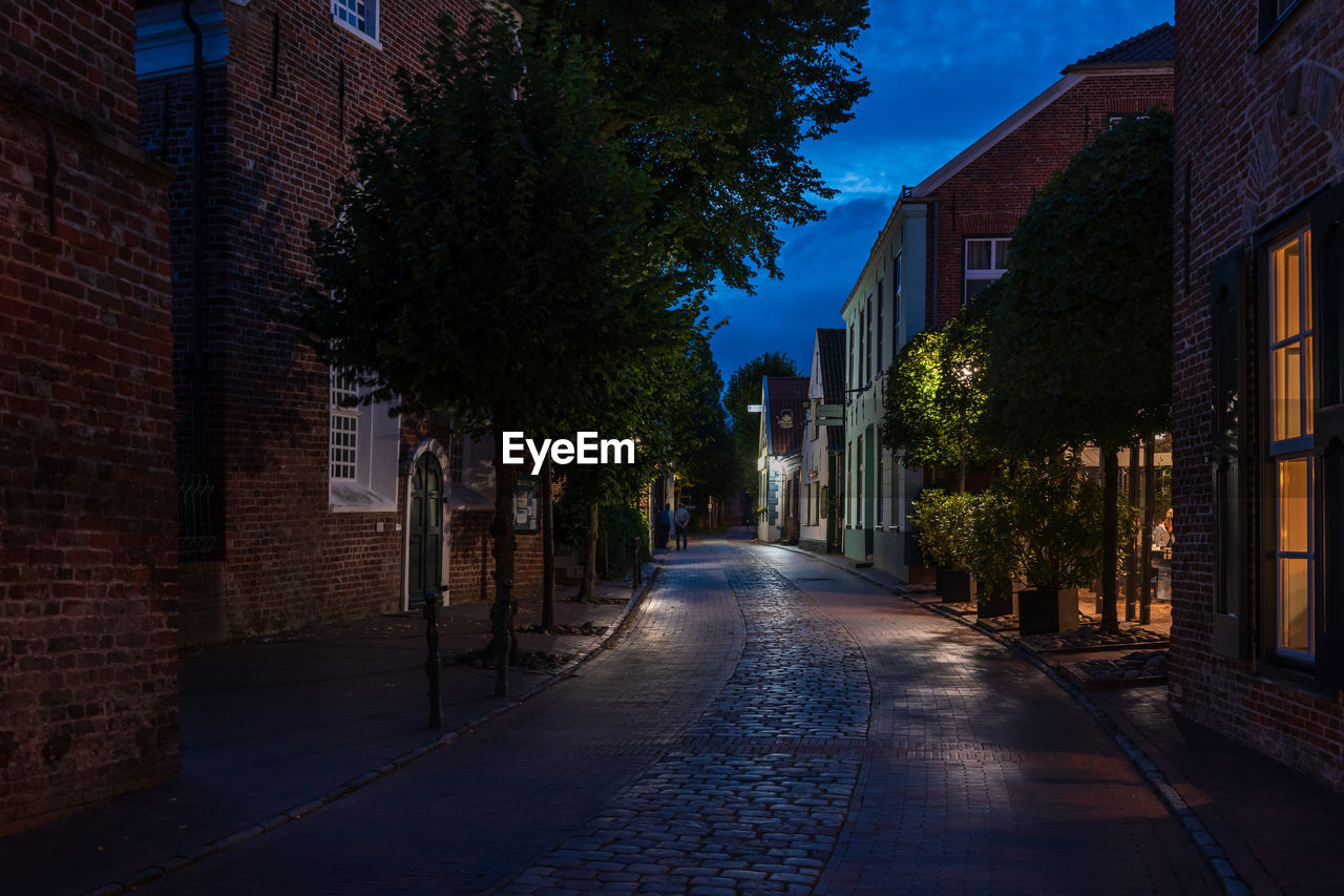 Empty road amidst buildings at night