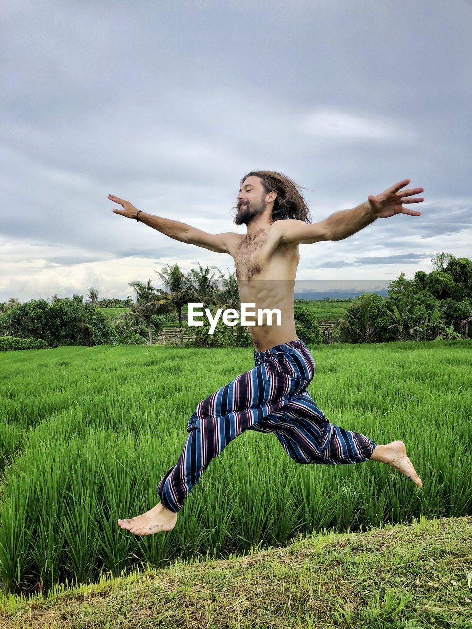 Shirtless man running on field against sky