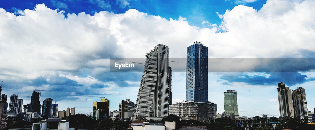 Panoramic view of buildings against cloudy sky