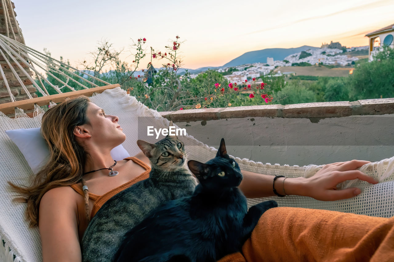 MIDSECTION OF WOMAN WITH CAT AGAINST SKY AT HOME