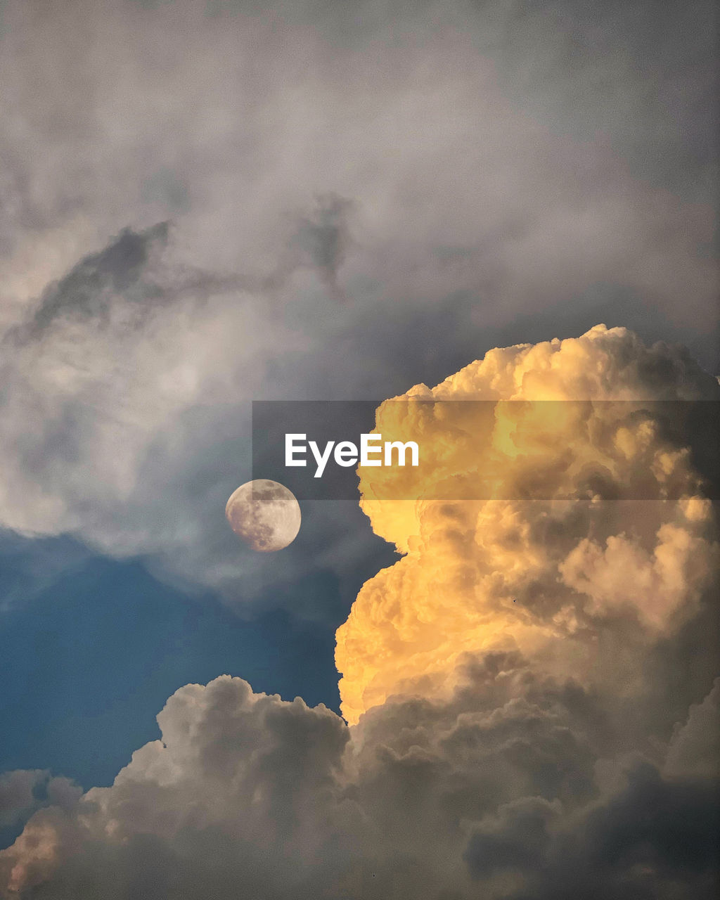 Low angle view of cloudscape against sky at sunset and moon