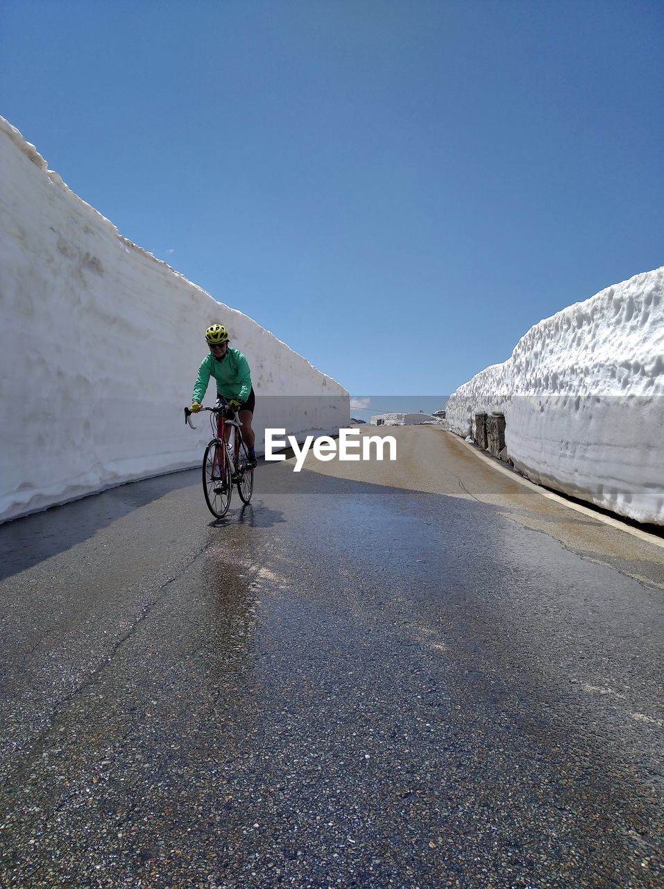 Man riding bicycle on road by snow during winter