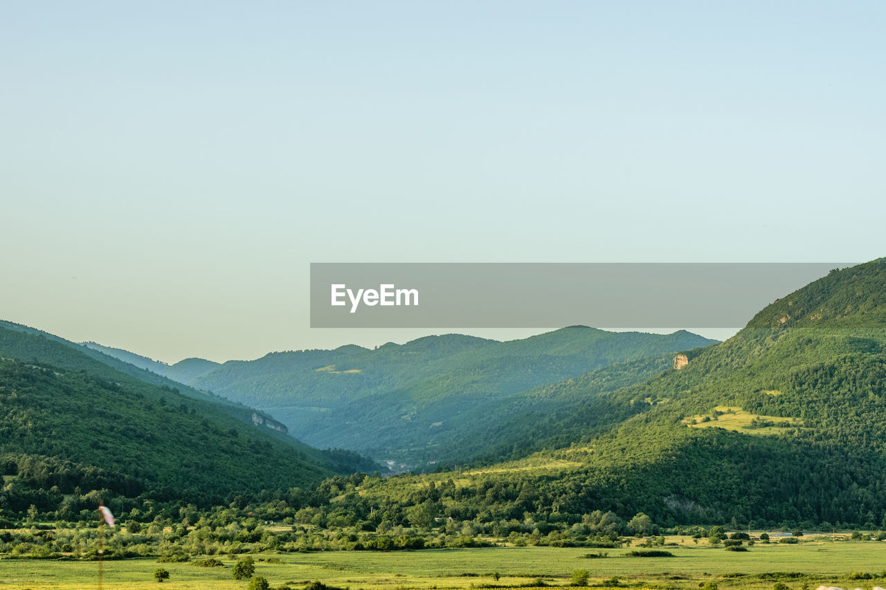 SCENIC VIEW OF LANDSCAPE AND MOUNTAINS AGAINST CLEAR SKY