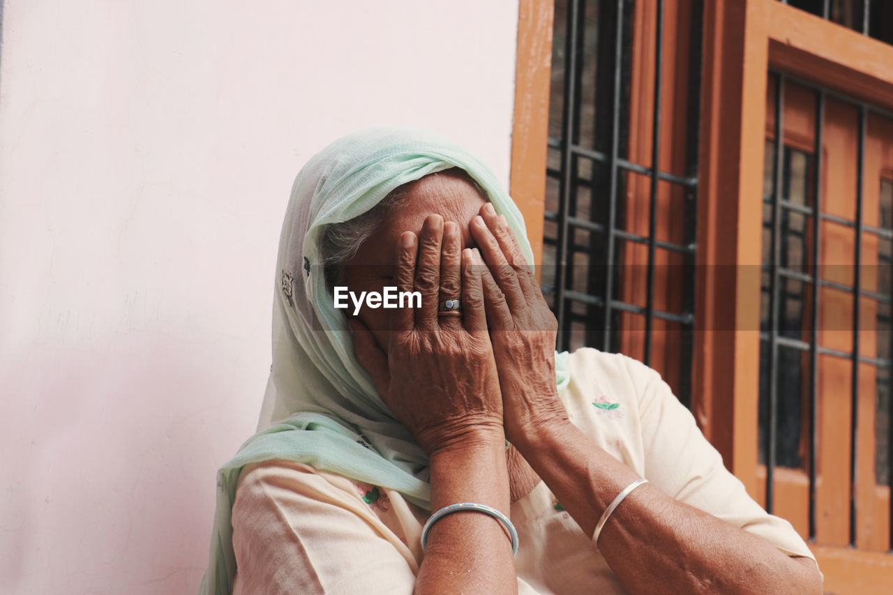 Close-up of senior woman covering face at home