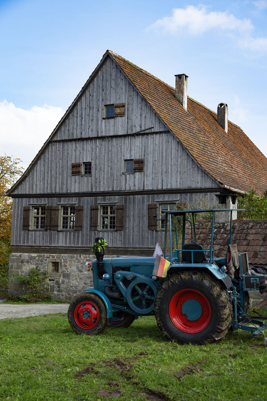 farm, tractor, rural area, sky, architecture, agriculture, rural scene, transportation, building exterior, agricultural equipment, landscape, nature, agricultural machinery, built structure, grass, vehicle, house, plant, building, mode of transportation, day, field, cloud, land, no people, agricultural building, lawn, barn, wheel, outdoors, land vehicle