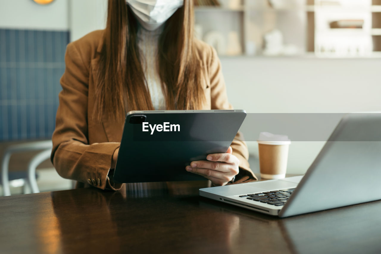 midsection of woman using laptop while sitting on table