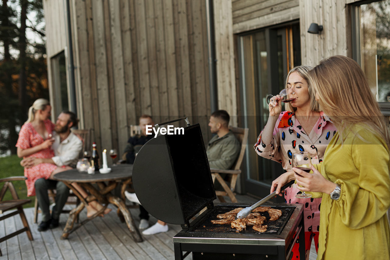 Friends having barbecue and drinking wine on patio