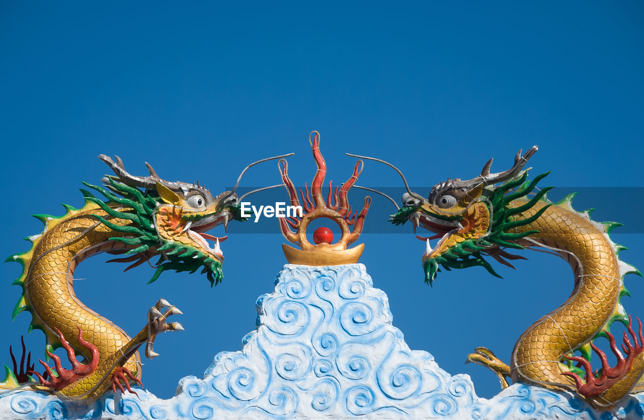 Chinese dragon statues against clear blue sky
