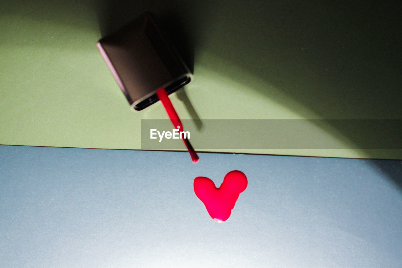 Close-up of red nail polish dripping on table