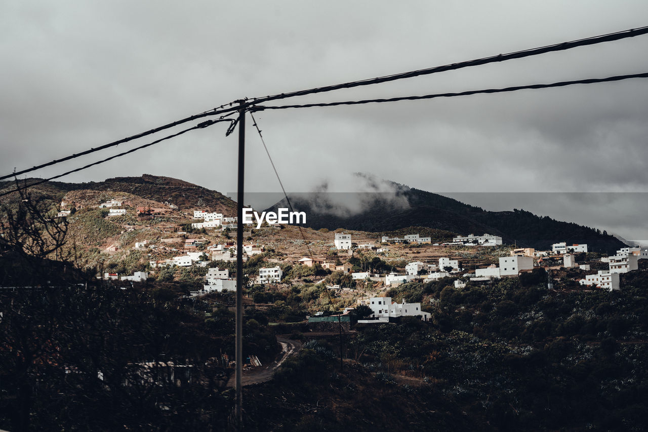 Low angle view of buildings on mountain against cloudy sky