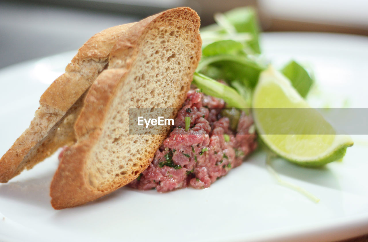 CLOSE-UP OF BREAD IN PLATE ON TABLE