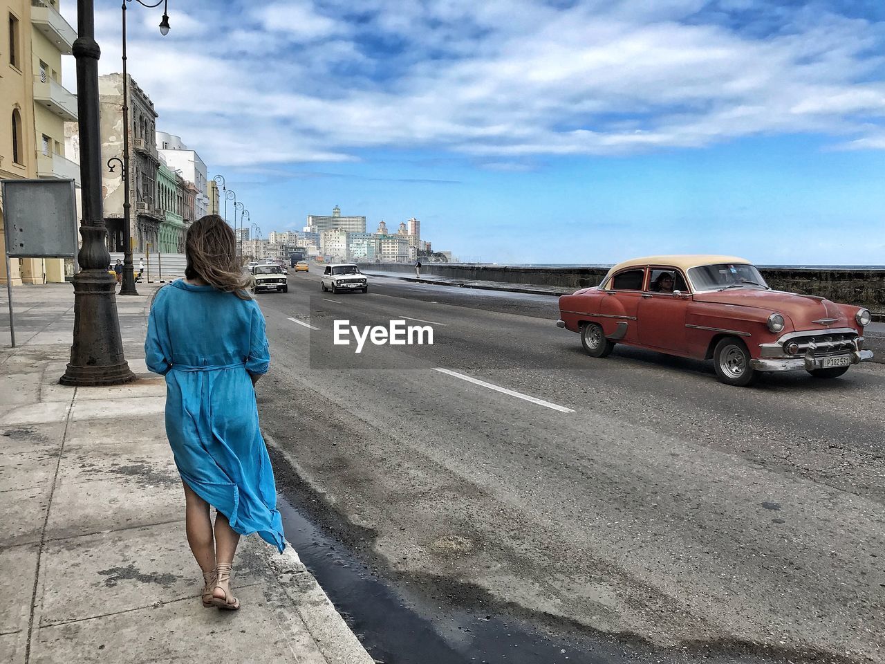 REAR VIEW OF WOMAN WALKING ON ROAD