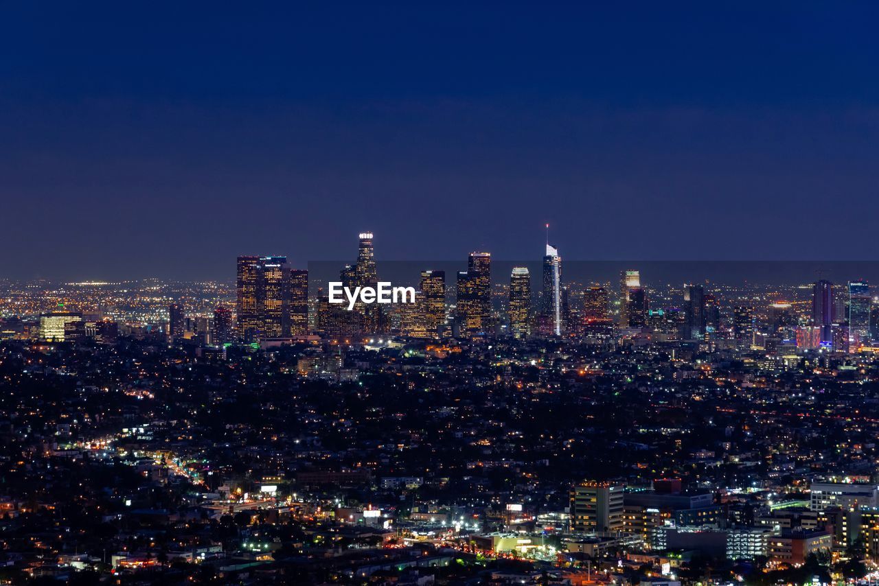 Illuminated cityscape against sky at night