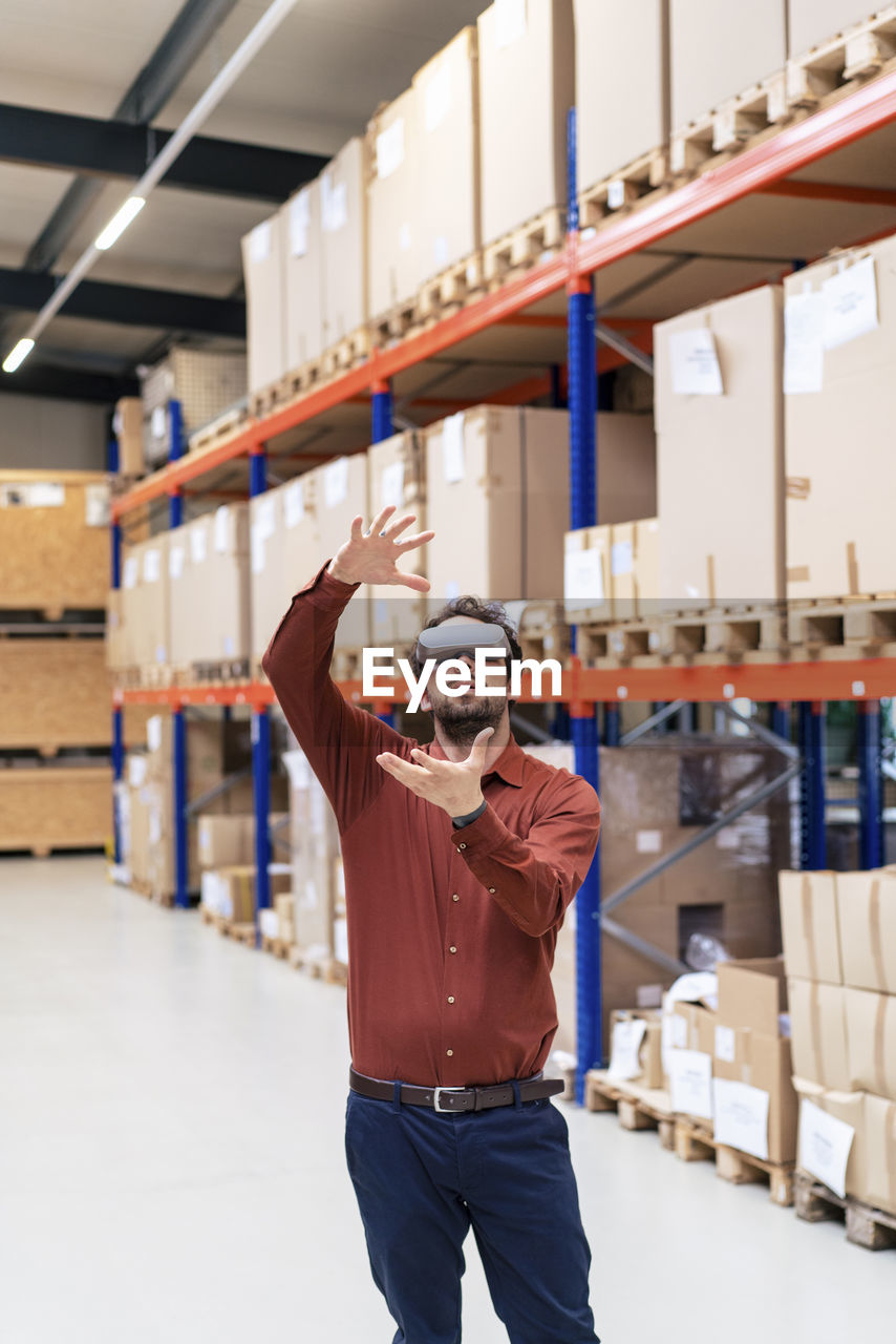 Businessman wearing virtual reality simulators gesturing in warehouse
