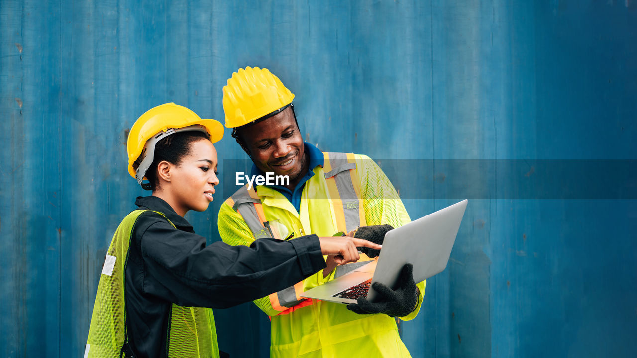 Engineers using laptop while standing in factory