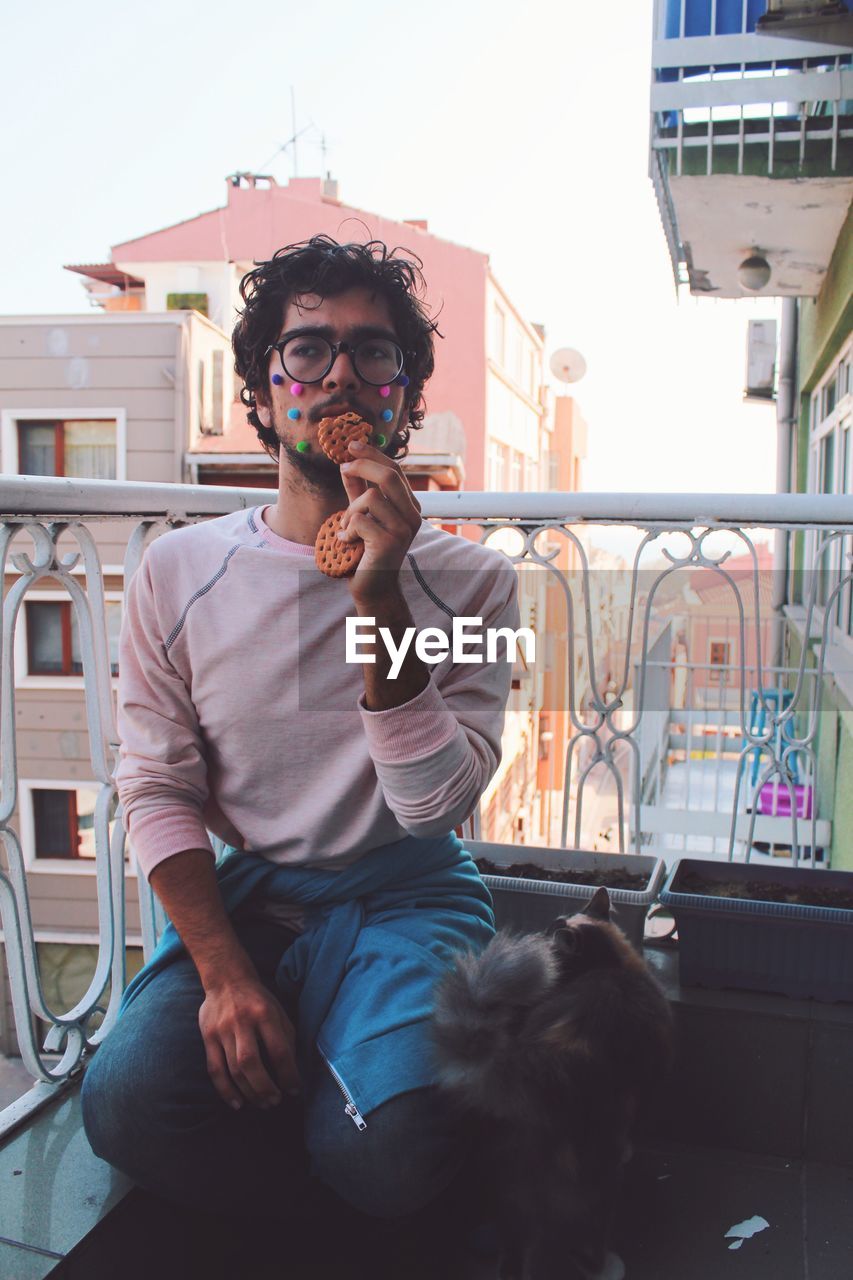 Man eating food while sitting in balcony