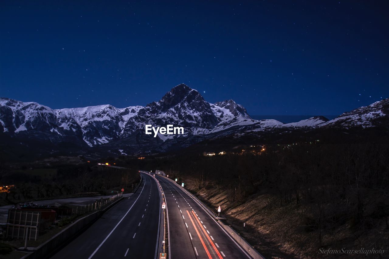 Light trails on road against clear sky at night