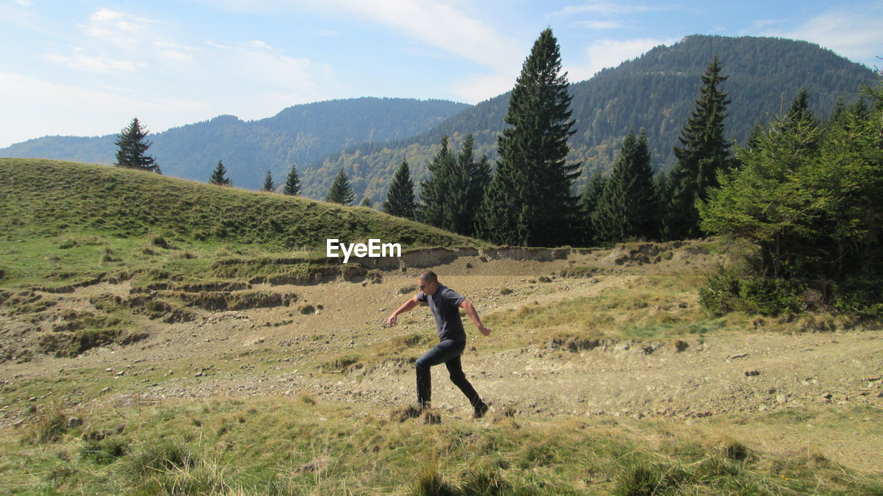 Man running on field against mountains