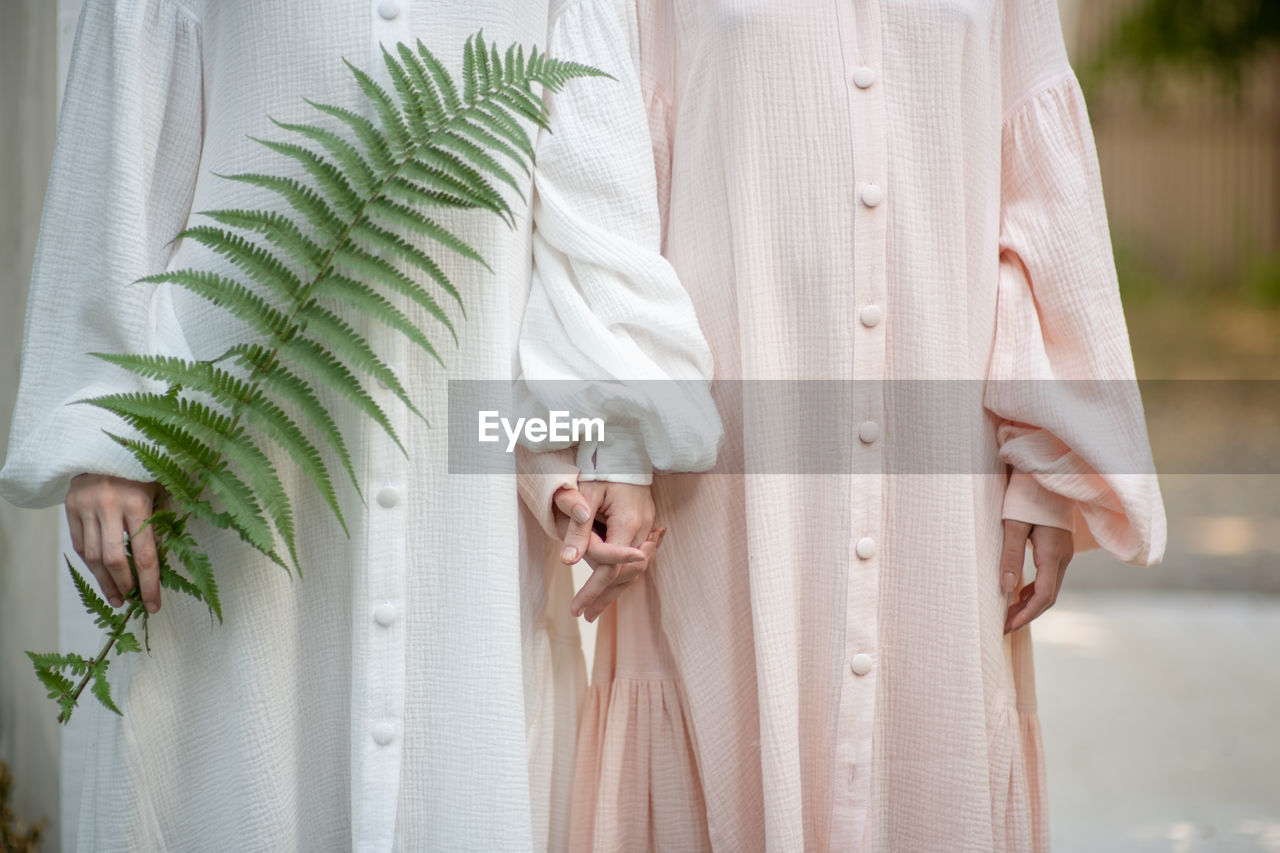 Midsection of women standing with plant