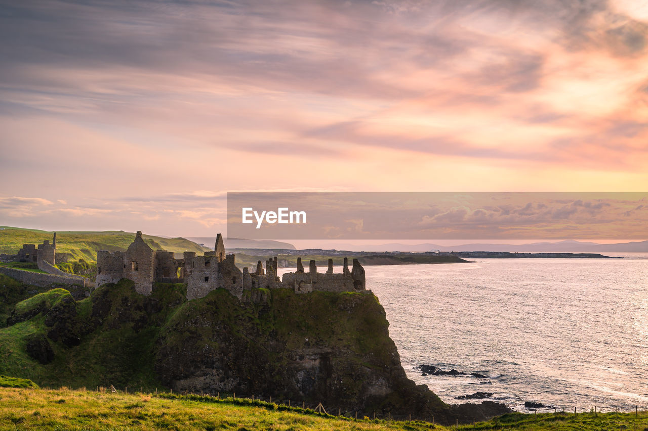 Dramatic sky over ruins of dunluce castle perched on the edge of cliff, northern ireland