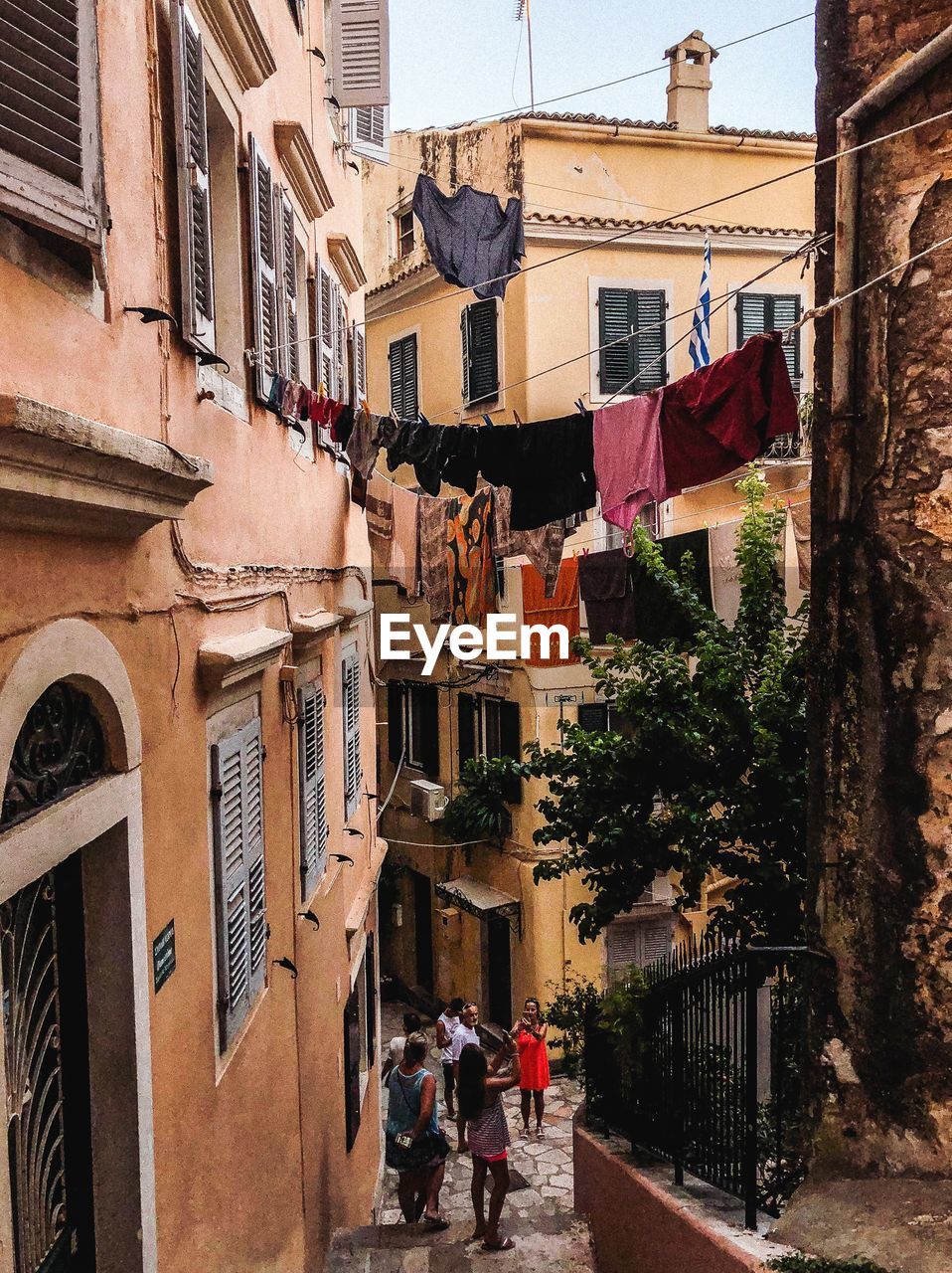 PEOPLE WALKING IN ALLEY AMIDST BUILDINGS