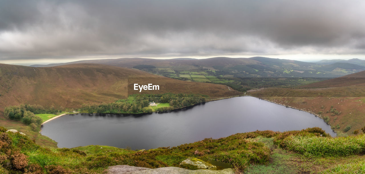 Panoramic view on lake lough bray with house, small forest and beach in wicklow mountains