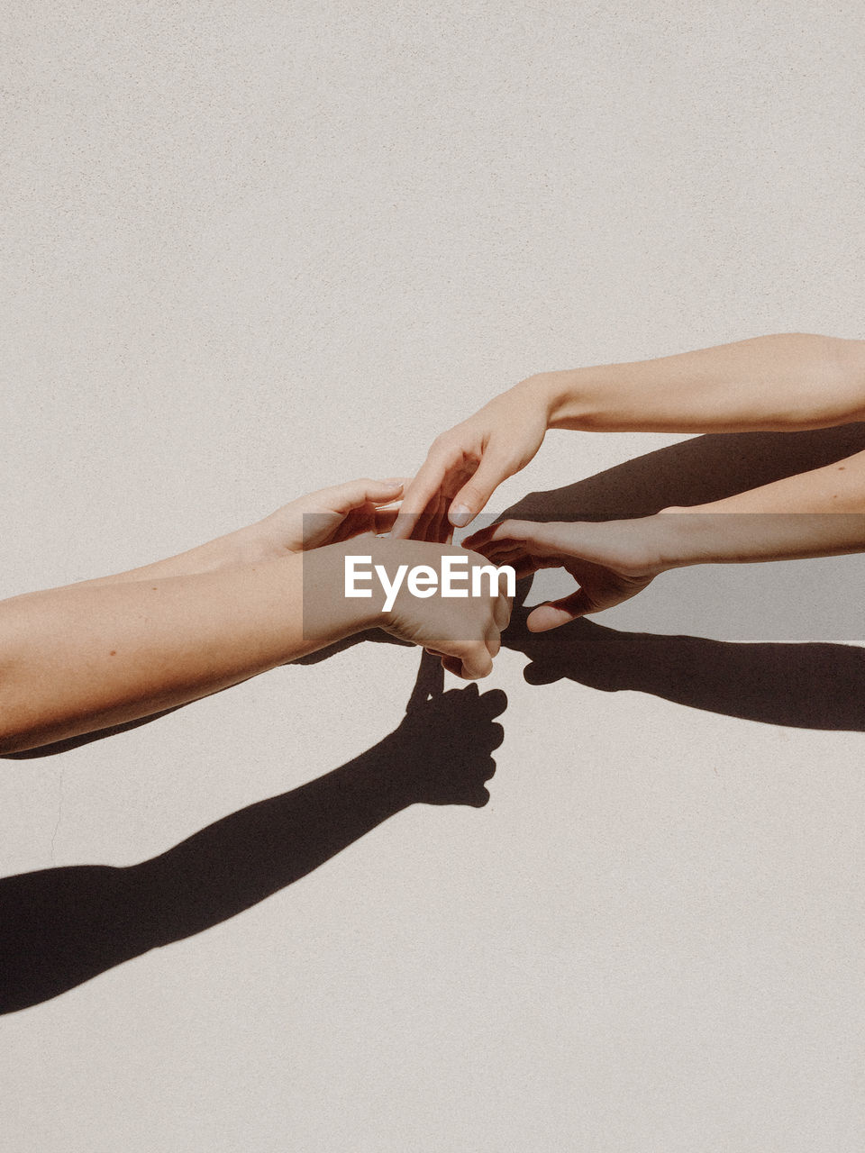 Cropped hands of women against gray wall