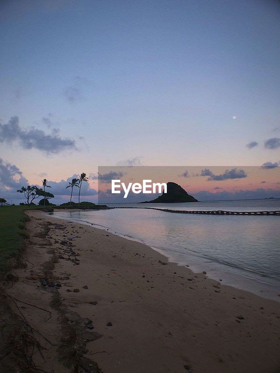 Scenic view of beach against sky at sunset