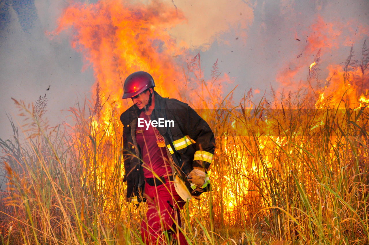 Firefighter standing by fire on field